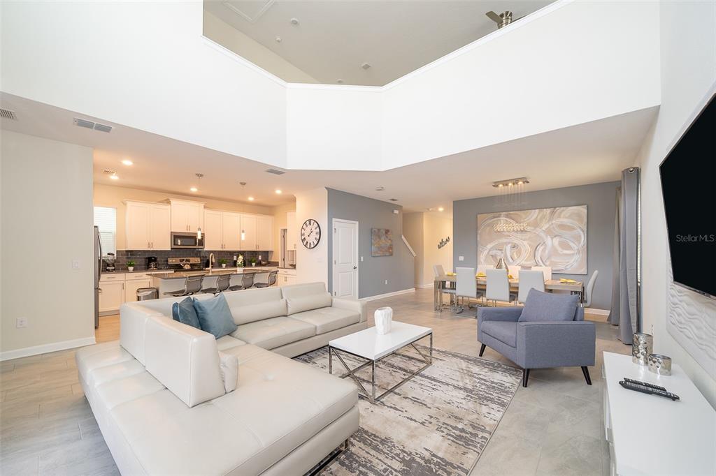 An open-concept living and dining area features a high ceiling, white cabinetry, and tile flooring — 2744 BOOKMARK DRIVE, KISSIMMEE, FL