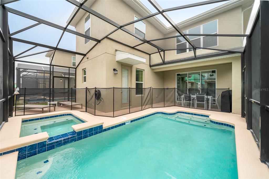 A screened-in patio features a swimming pool, a hot tub, and a dining set — 2744 BOOKMARK DRIVE, KISSIMMEE, FL
