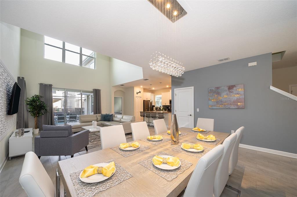 A dining room with a long table and chandelier opens into a living area and kitchen — 2744 BOOKMARK DRIVE, KISSIMMEE, FL