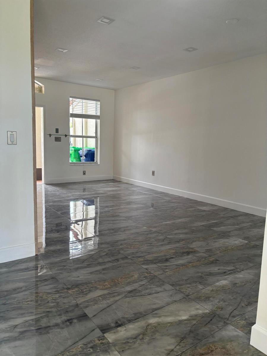 An empty room features glossy, gray marble-patterned tile flooring and white walls with recessed lighting — 254 Riverwalk Circle # 254, Sunrise FL 33326, SUNRISE, FL