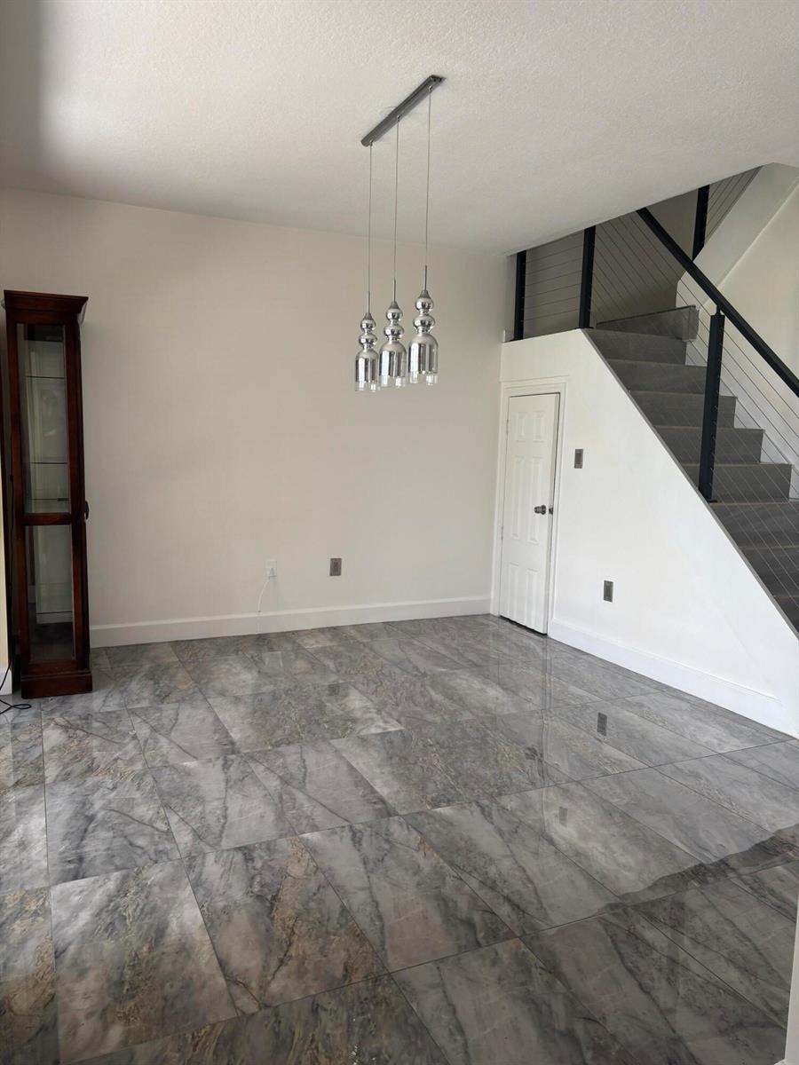 A dining area features gray marble-look tile flooring, a modern pendant light, and a staircase — 254 Riverwalk Circle # 254, Sunrise FL 33326, SUNRISE, FL
