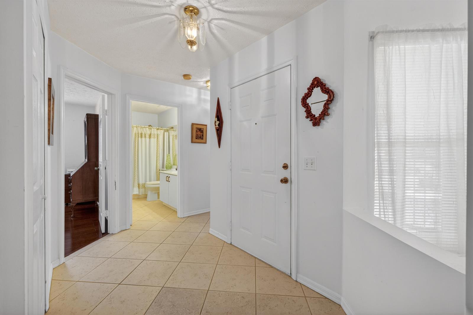 An entryway with tile flooring, a white front door, and a view into a bathroom — 6737 Campanilla, Fort Pierce FL 34951, FORT PIERCE, FL