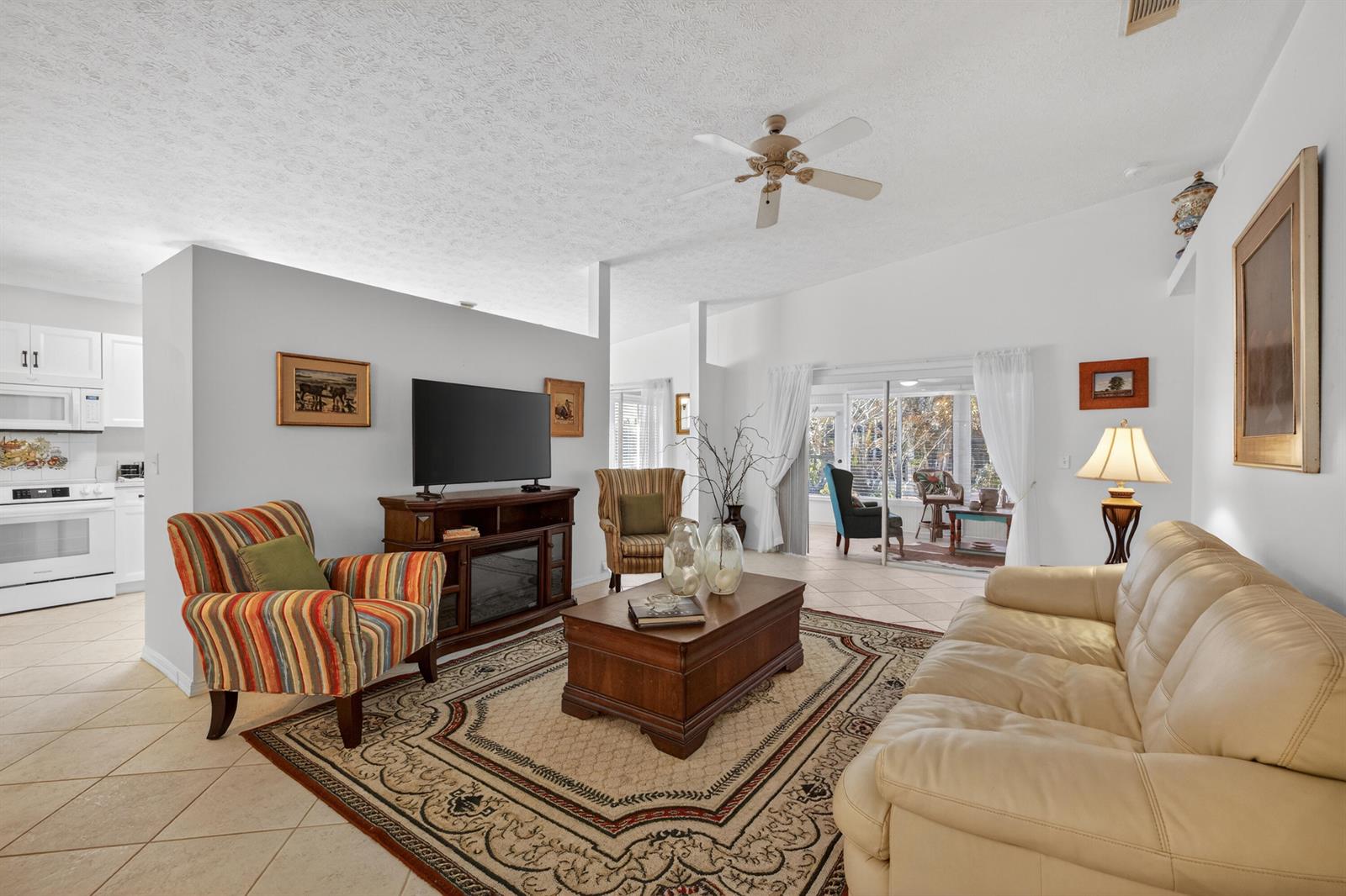 A living room features a beige leather sofa, a striped armchair, and a wooden coffee table — 6737 Campanilla, Fort Pierce FL 34951, FORT PIERCE, FL