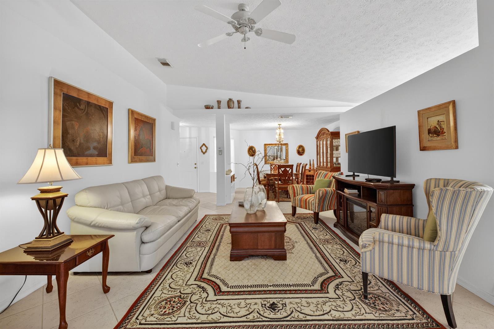 A living room features a white sofa, patterned armchairs, a wooden coffee table, and area rug — 6737 Campanilla, Fort Pierce FL 34951, FORT PIERCE, FL