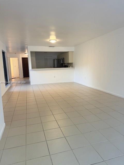 A tiled hallway leads to a living area with a large window overlooking a courtyard — 13371 SW 89th Ter # F, Miami FL 33186, MIAMI, FL