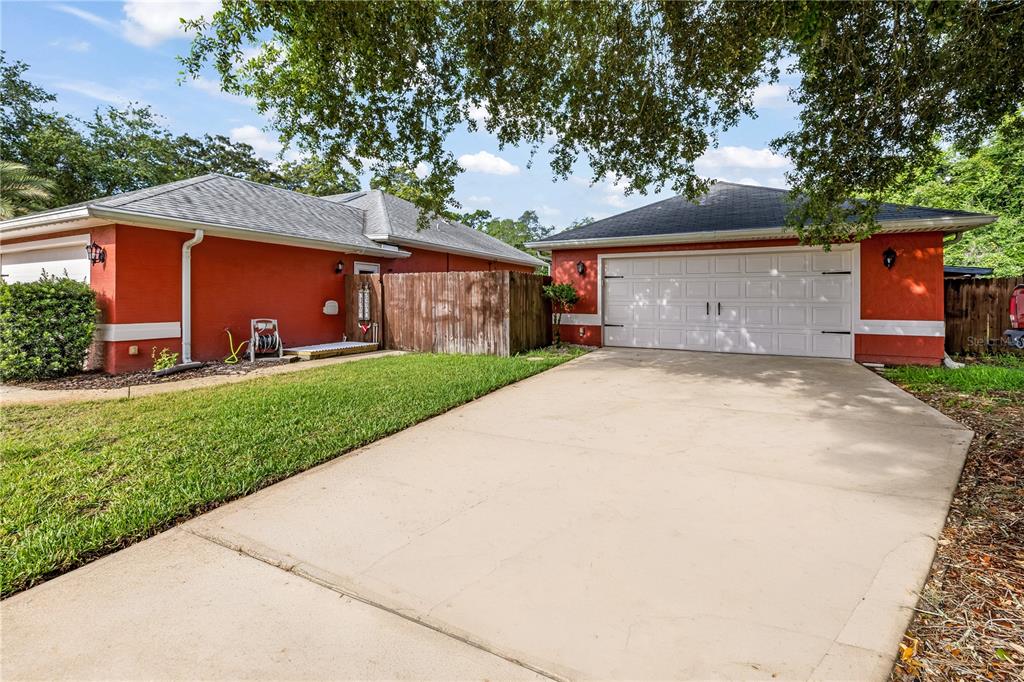 A concrete driveway leads to a two-car garage attached to a red house — 7 FARVER LANE, PALM COAST, FL