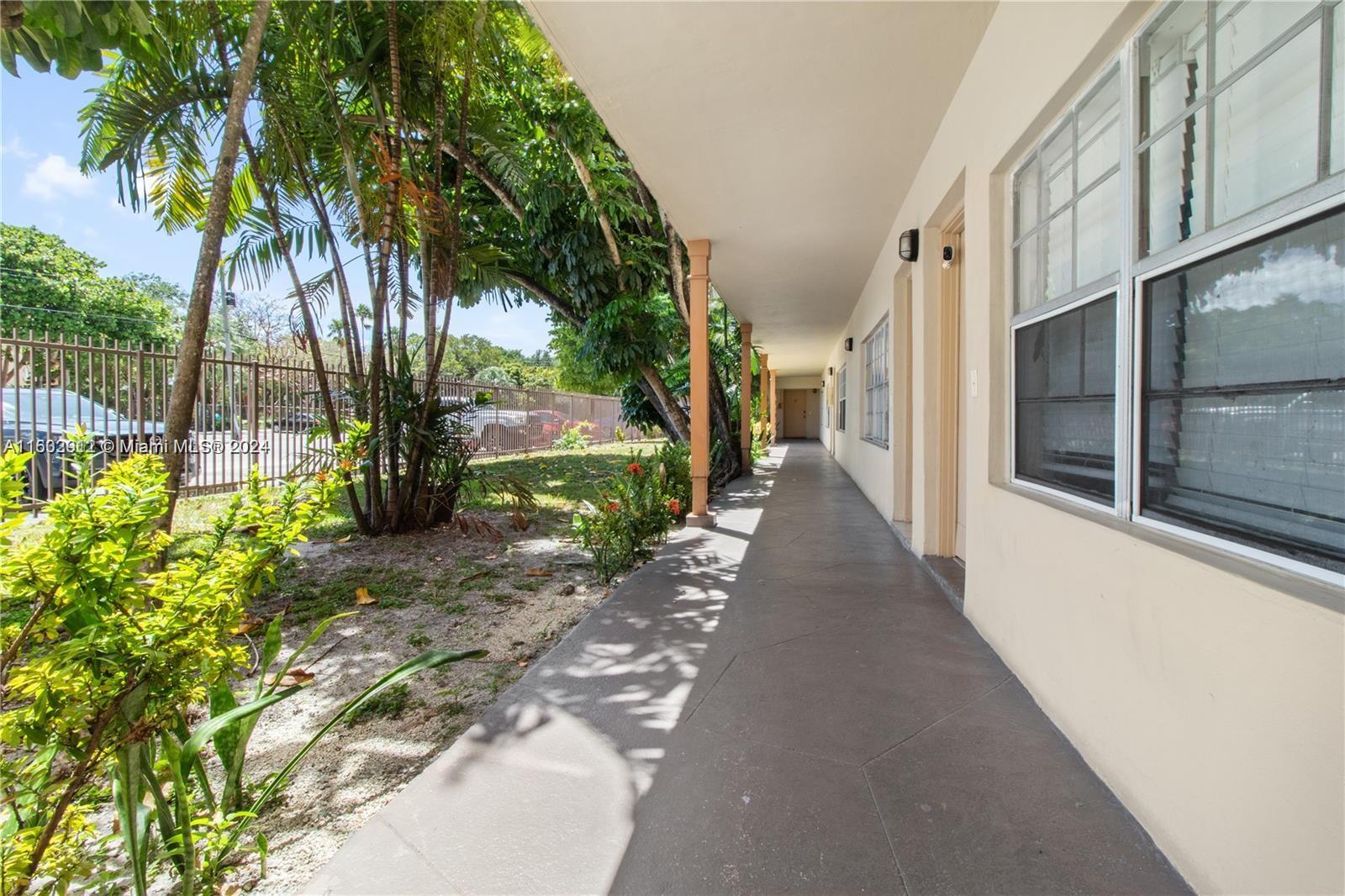 An outdoor walkway runs along the side of a building with windows and doors — 11855 NE 19th Dr # 1, North Miami FL 33181, NORTH MIAMI, FL