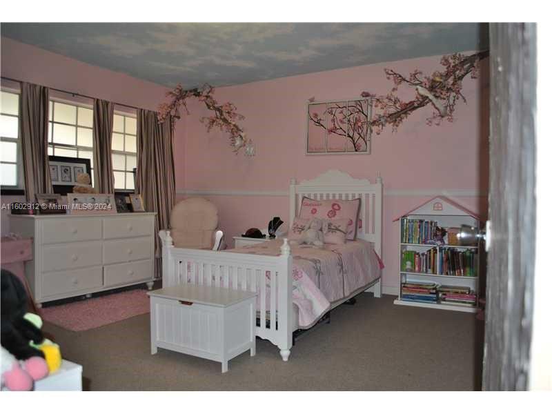 A pink bedroom features a white bed, a dresser, a bookshelf, and cherry blossom wall decals — 11855 NE 19th Dr # 1, North Miami FL 33181, NORTH MIAMI, FL