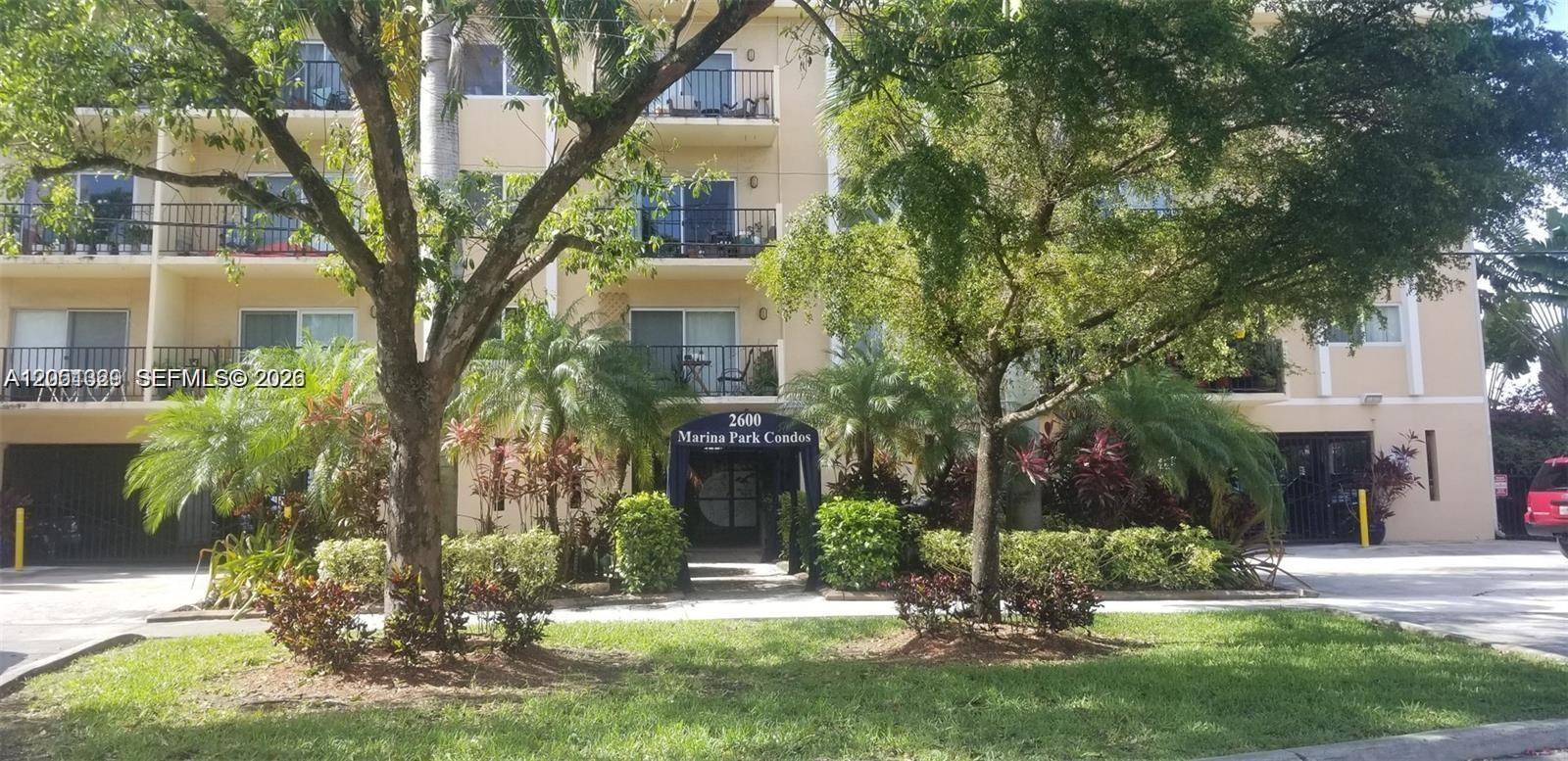 The exterior of a multi-story apartment building features balconies, lush landscaping, and a covered entrance — 2600 NE 135th St # A, North Miami FL 33181, NORTH MIAMI, FL