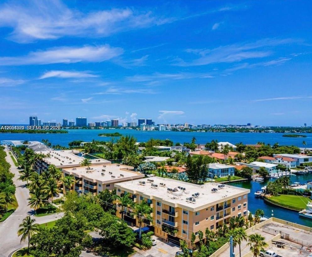 An aerial view shows low-rise apartment buildings surrounded by palm trees near a coastal waterway — 2600 NE 135th St # A, North Miami FL 33181, NORTH MIAMI, FL