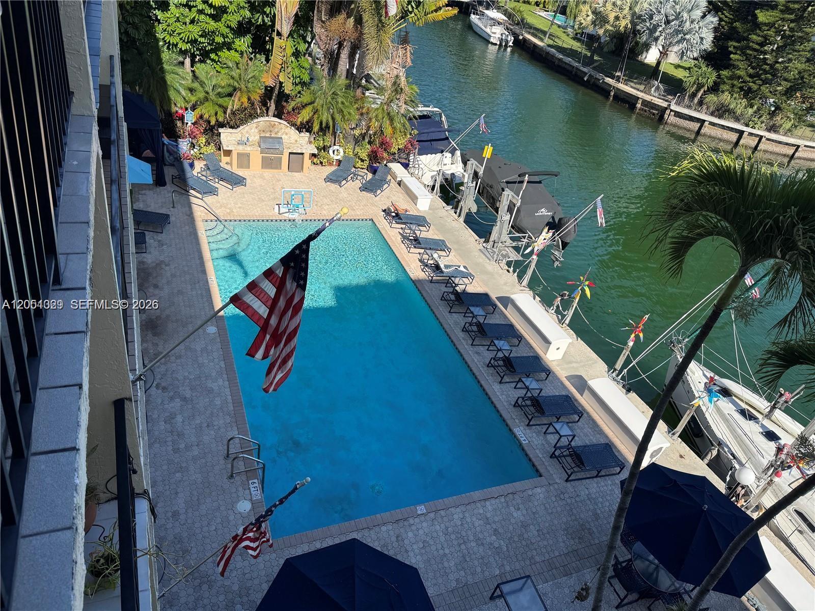 An elevated view shows a rectangular swimming pool with lounge chairs beside a canal — 2600 NE 135th St # A, North Miami FL 33181, NORTH MIAMI, FL