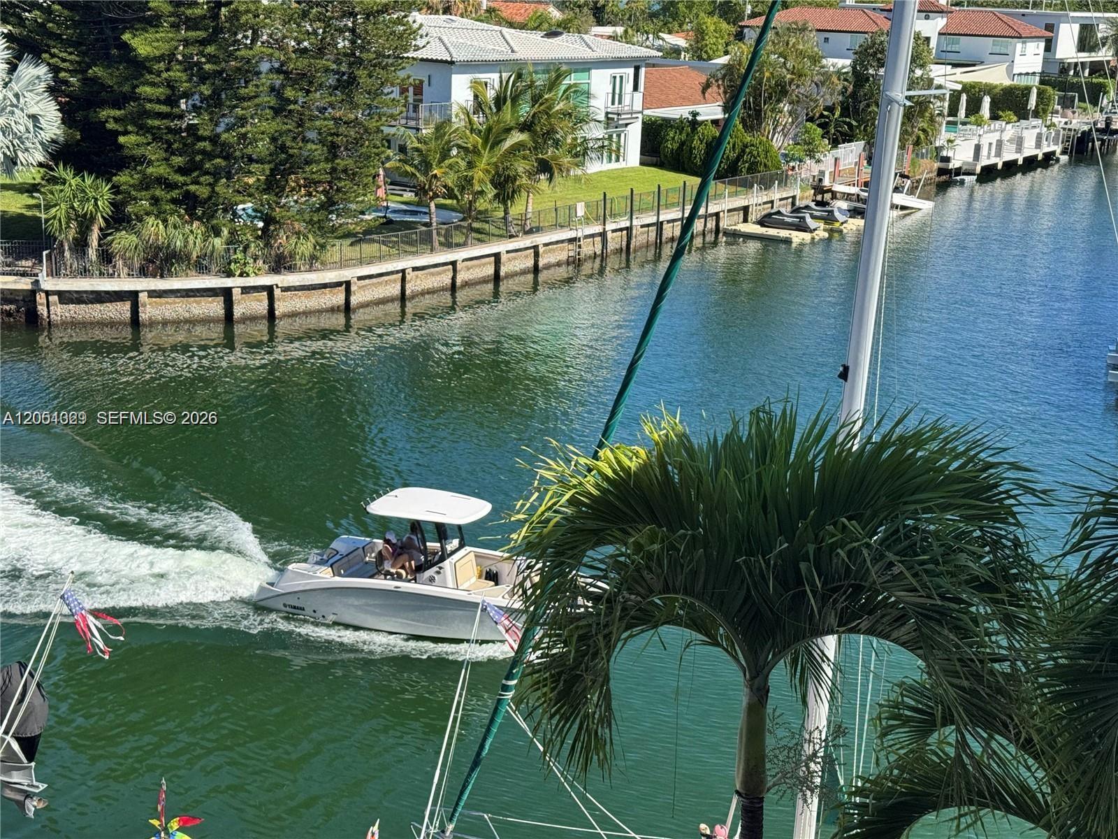 A white motorboat travels along a canal lined with houses and palm trees — 2600 NE 135th St # A, North Miami FL 33181, NORTH MIAMI, FL