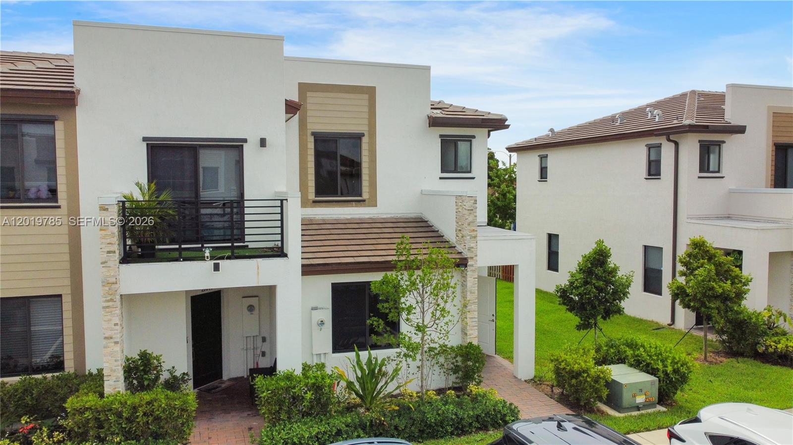 A two-story townhouse with a balcony, stone accents, and a paved walkway — 21035 NE 8th Ave, Miami FL 33179, MIAMI, FL