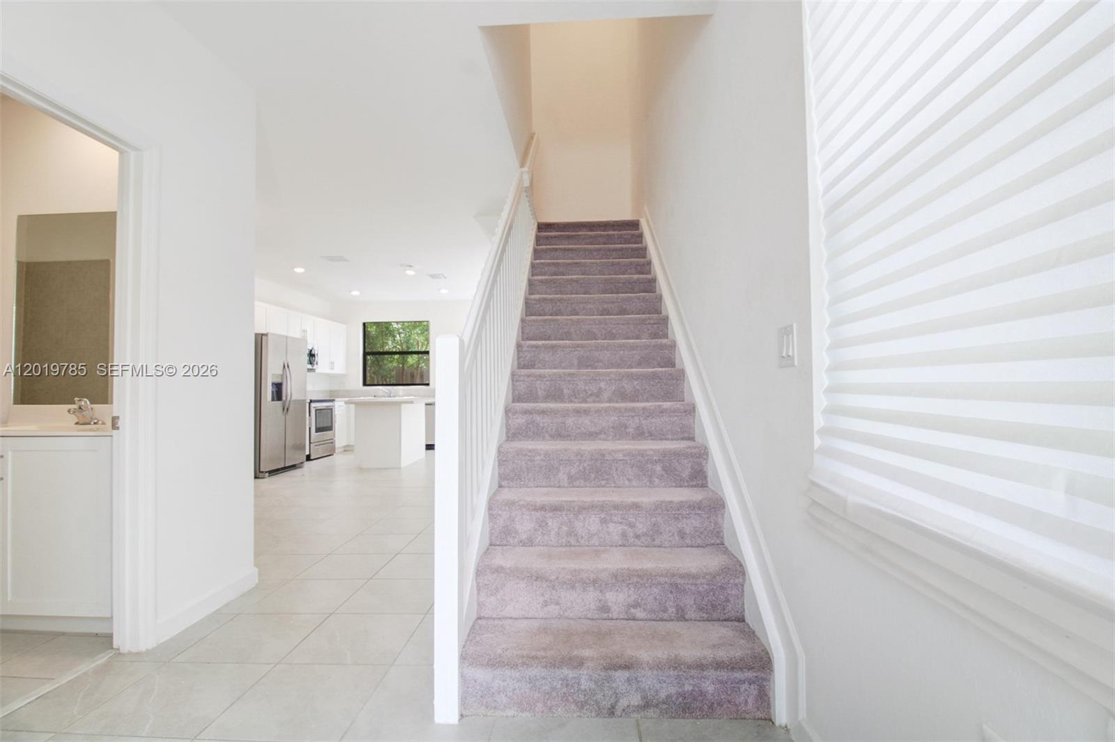 A carpeted staircase leads upward next to a tiled floor kitchen area — 21035 NE 8th Ave, Miami FL 33179, MIAMI, FL