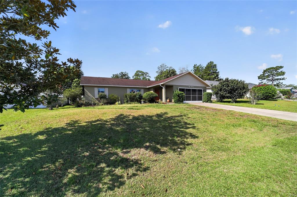 A single-story house with a tan exterior, a brown roof, and a screened-in garage — 494 MARION OAKS MANOR, OCALA, FL