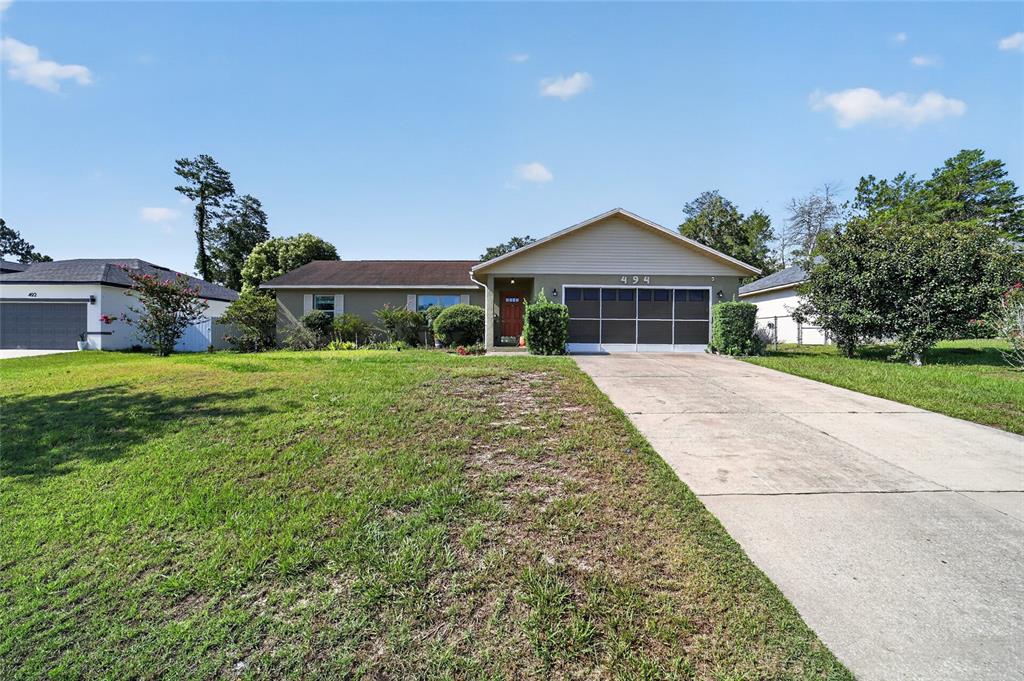 A single-story house with a concrete driveway, a front-facing garage, and a lawn — 494 MARION OAKS MANOR, OCALA, FL