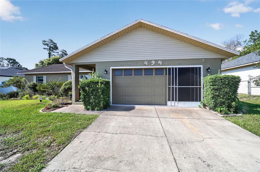 A single-story house with a beige exterior, a garage, and a concrete driveway — 494 MARION OAKS MANOR, OCALA, FL
