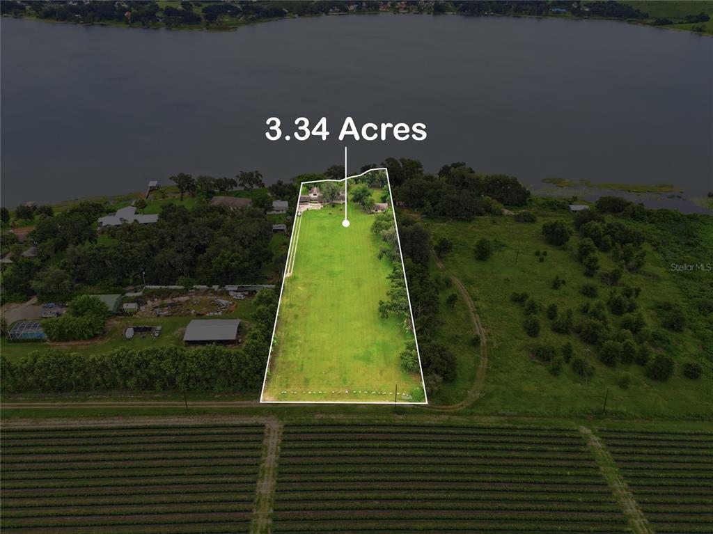 An aerial view shows a rectangular lot with a house bordering a large lake — 767 EDISON ROAD, AUBURNDALE, FL