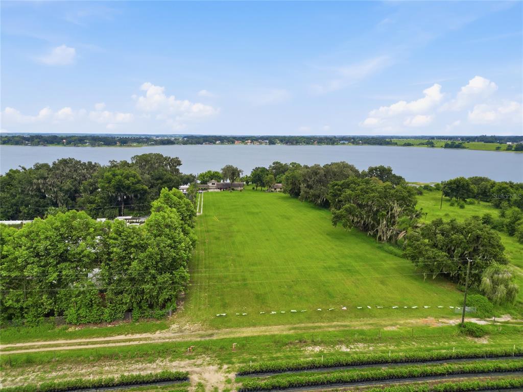 An aerial view shows a large, rectangular grassy lot extending toward a lake — 767 EDISON ROAD, AUBURNDALE, FL
