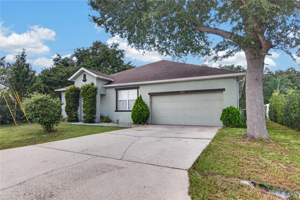 A single-story house with a light green exterior, a two-car garage, and a concrete driveway — 626 BALDWIN DRIVE, KISSIMMEE, FL