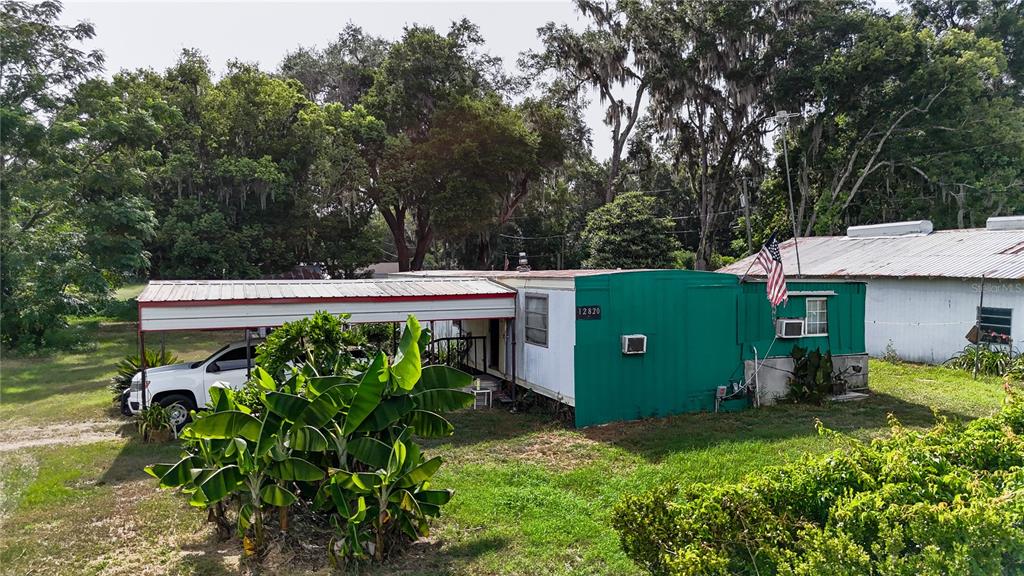 A green and white mobile home with a carport and an American flag outside — 12818 NE OLD JACKSONVILLE ROAD, ANTHONY, FL