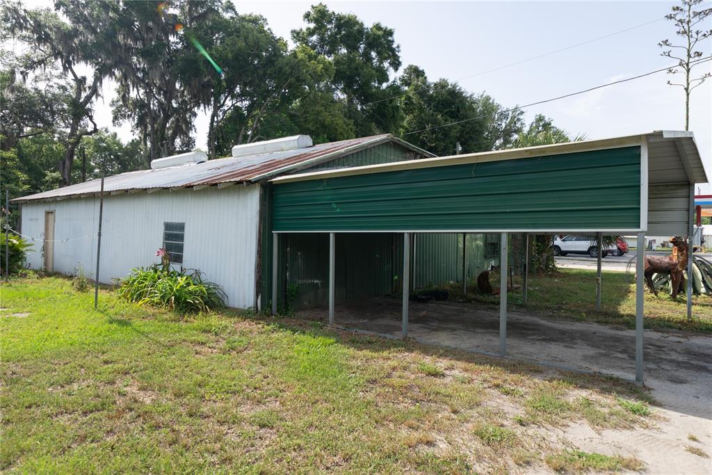 A metal-sided building with a green carport extension sits on a grassy lot — 12818 NE OLD JACKSONVILLE ROAD, ANTHONY, FL