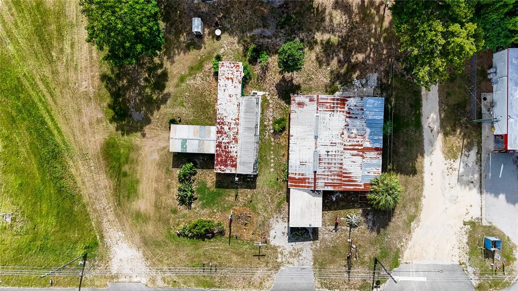 An aerial view shows two structures with weathered metal roofs situated on a grassy lot — 12818 NE OLD JACKSONVILLE ROAD, ANTHONY, FL