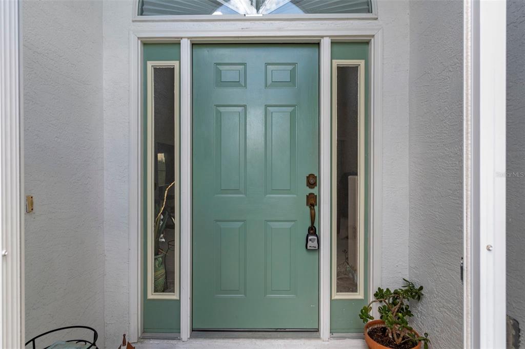 A sage green front door with sidelights and a transom window sits in an entryway — 201 N GOLF HARBOR PATH, INVERNESS, FL