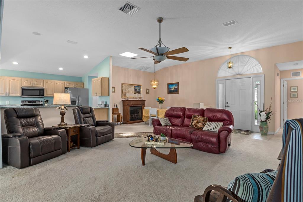 A living room with a red sofa, two recliners, a fireplace, and an open kitchen — 201 N GOLF HARBOR PATH, INVERNESS, FL