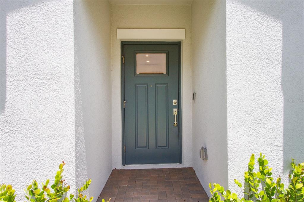 A teal front door with a small window is set within a white stucco entryway — 16657 SHELL BAY DRIVE, LAND O LAKES, FL