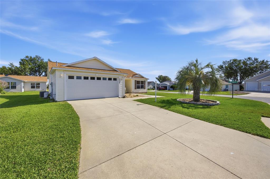 A single-story house with a white garage door, beige siding, and a concrete driveway — 17705 SE 93RD HAWTHORNE AVENUE, THE VILLAGES, FL