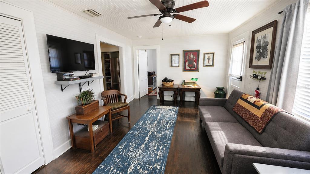 A living room features dark wood floors, a gray sofa, and a ceiling fan — 18758 NW 243RD TERRACE, HIGH SPRINGS, FL