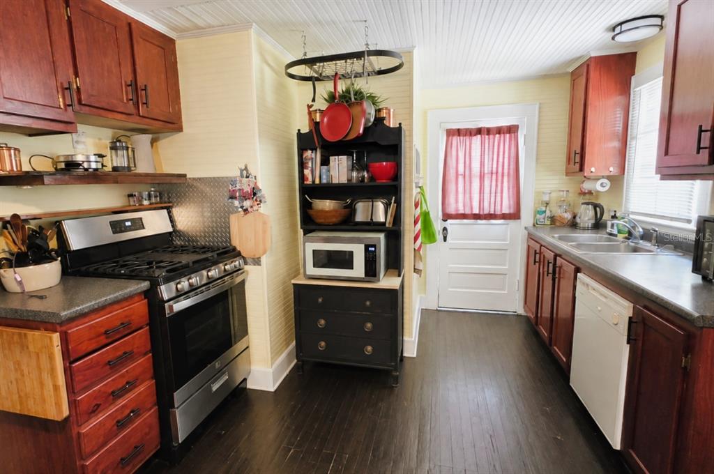 A kitchen with dark wood cabinets, black appliances, a microwave hutch, and dark wood flooring — 18758 NW 243RD TERRACE, HIGH SPRINGS, FL