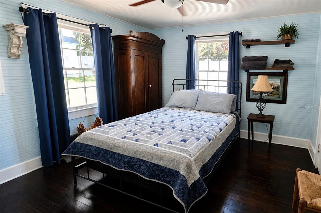 A bedroom features light blue beadboard walls, a dark wood wardrobe, and a metal bed frame — 18758 NW 243RD TERRACE, HIGH SPRINGS, FL