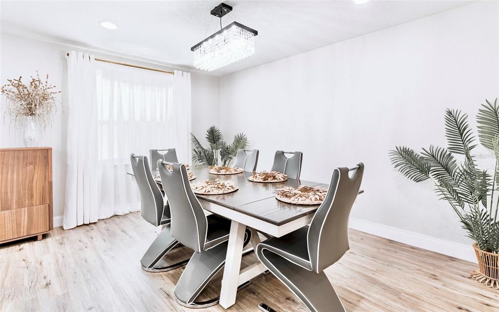 A dining room features a rectangular table with six grey chairs under a crystal chandelier — 6220 INTERBAY, TAMPA, FL