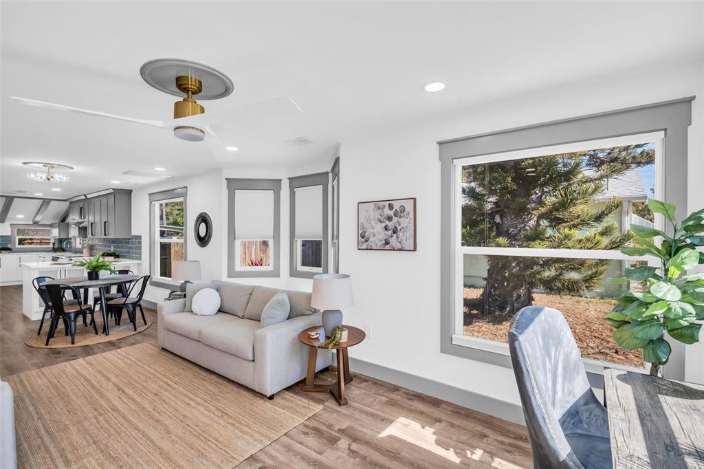A living room with a grey sofa, wood-look flooring, and an open kitchen in view — 4933 NEWTON AVENUE S, GULFPORT, FL