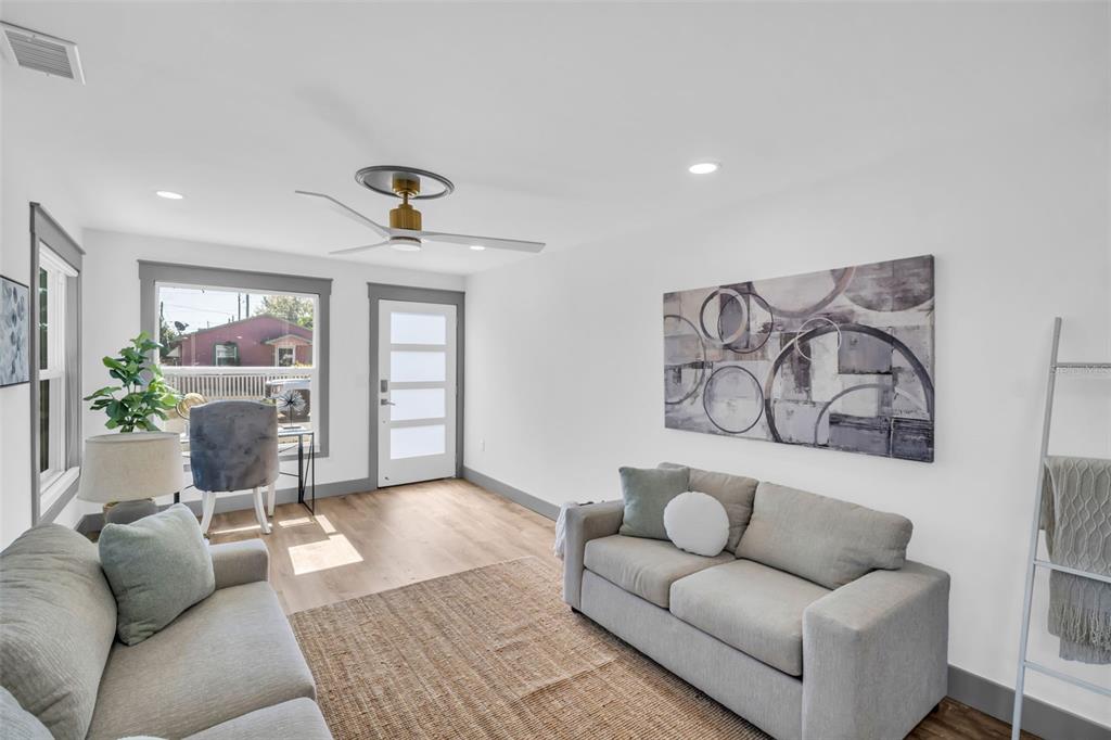 A living room features two gray sofas, a jute rug, and a modern ceiling fan — 4933 NEWTON AVENUE S, GULFPORT, FL