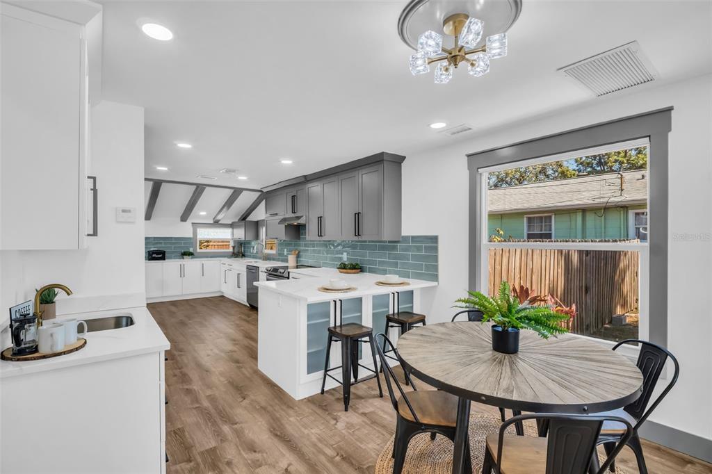 A kitchen and dining area with gray cabinets, white countertops, and a round wooden table — 4933 NEWTON AVENUE S, GULFPORT, FL