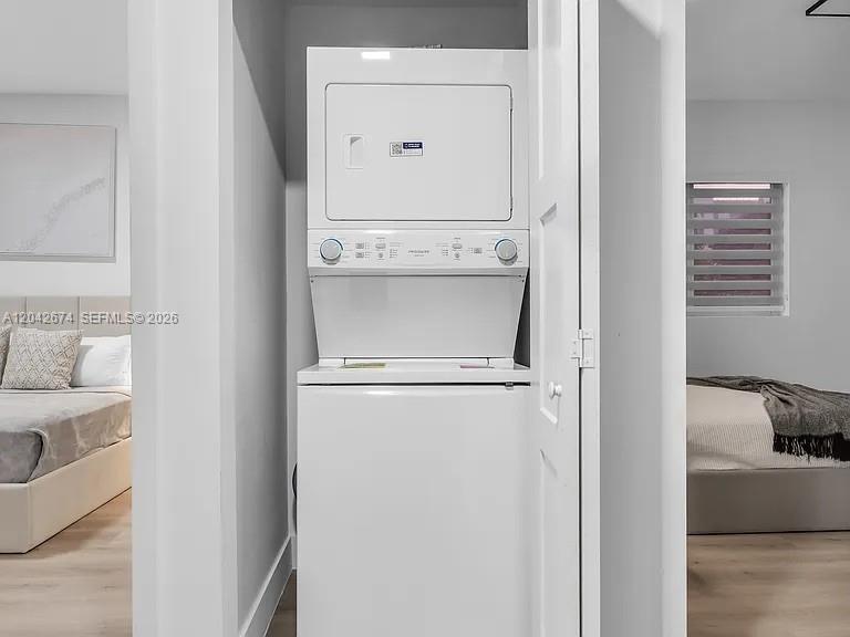 A stacked white washer and dryer unit sits in a closet between two bedrooms — 3728 NW 19th Ave # 305, Miami FL 33142, MIAMI, FL
