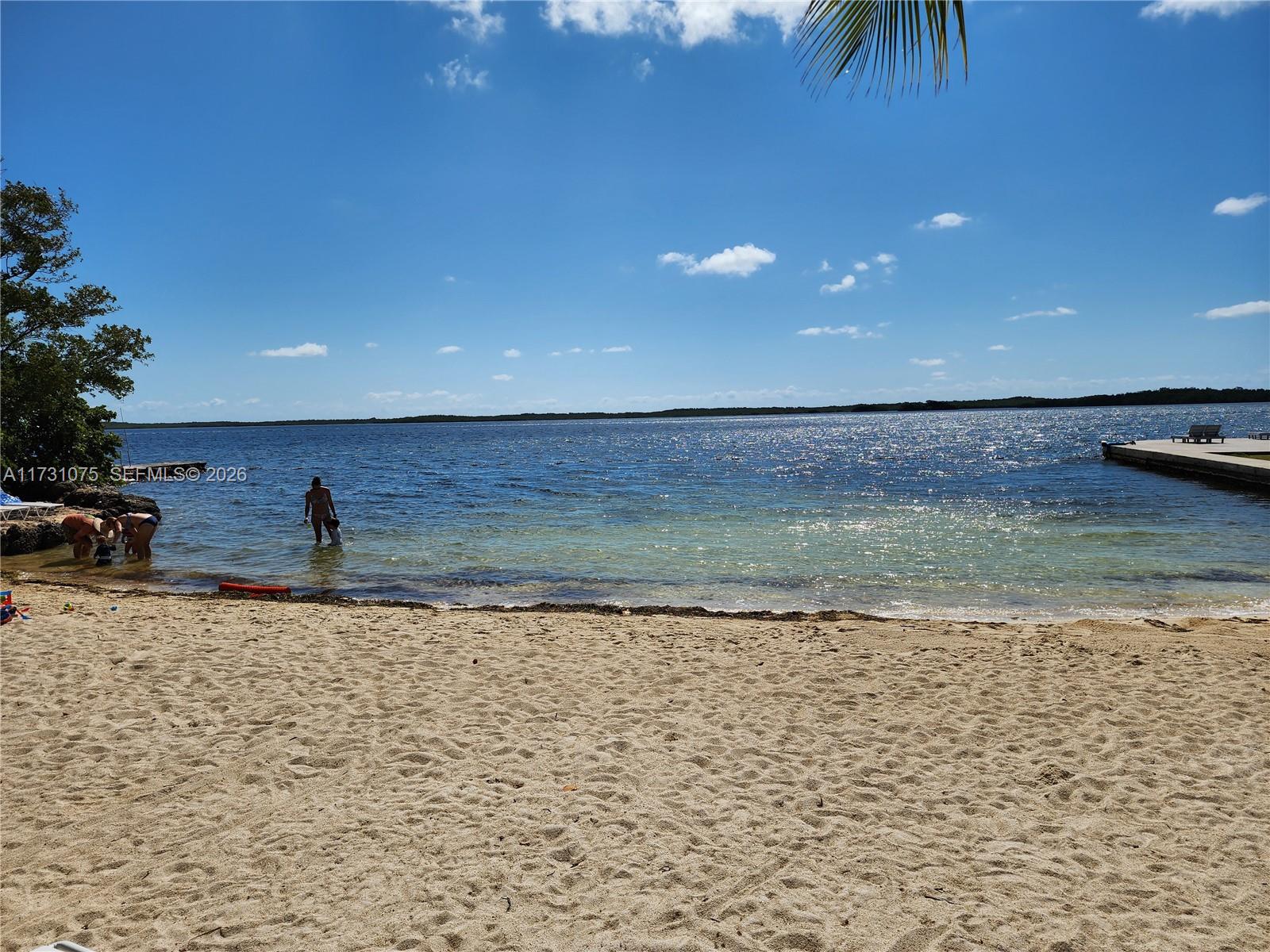 A sandy beach leads into a calm bay with people wading in the shallow water — 35 Bass Ave., Key Largo FL 33037, KEY LARGO, FL