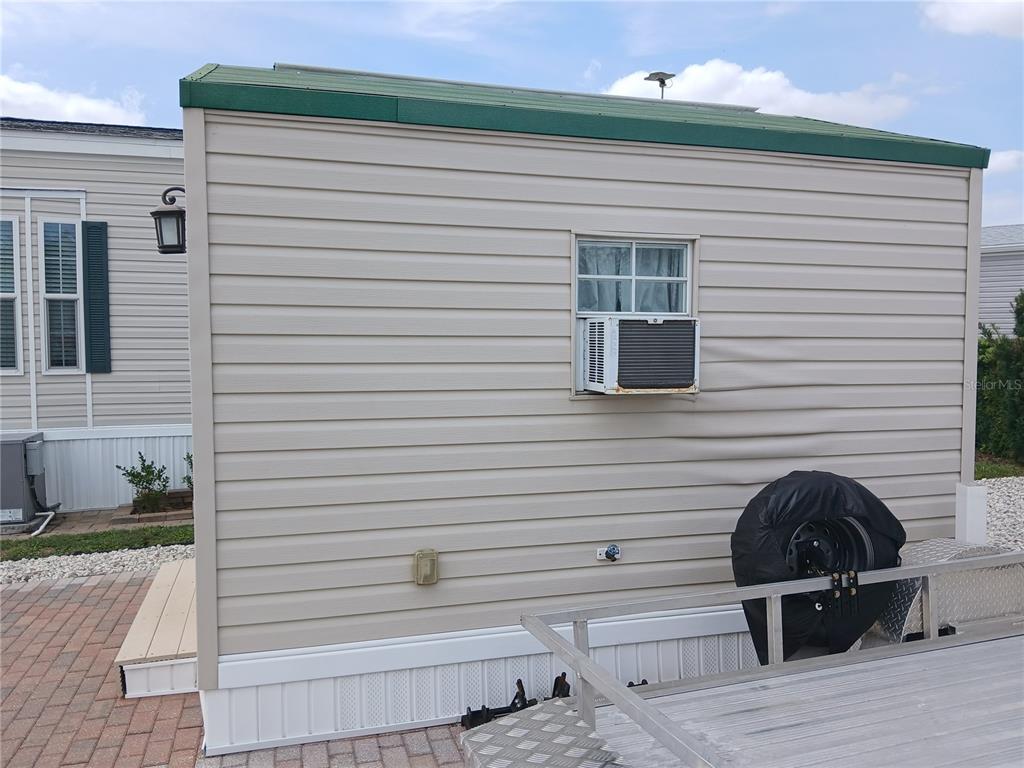 The exterior side of a tan mobile home features a window air conditioning unit — 2442 LIMEWOOD AVENUE, CLERMONT, FL