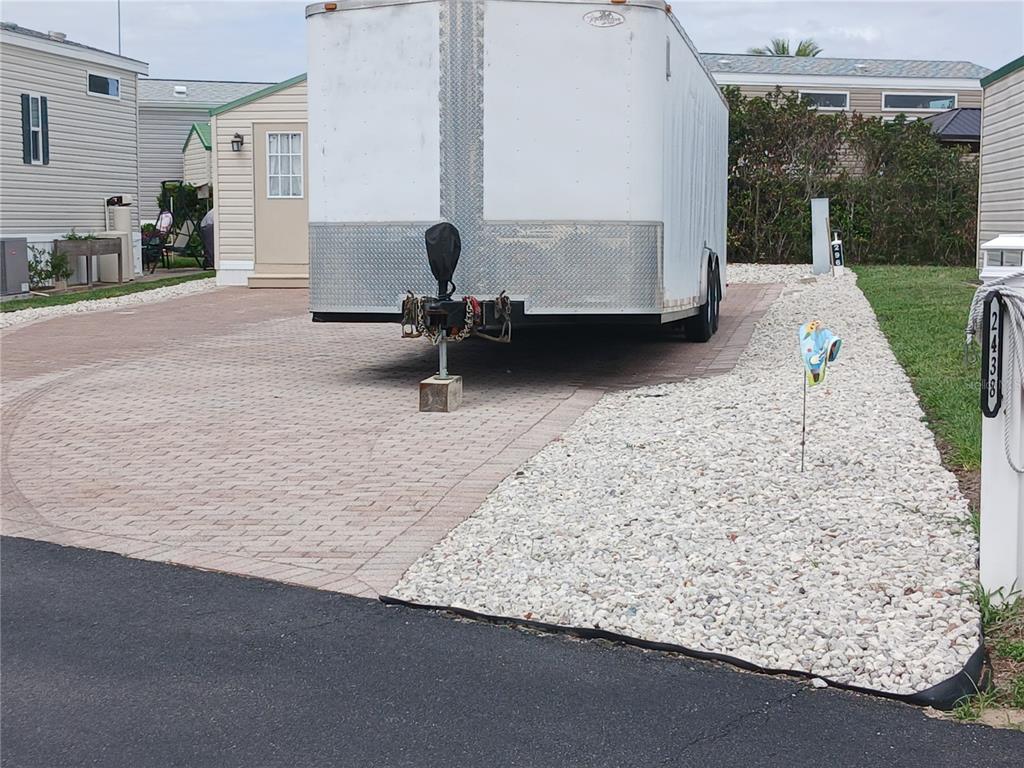 A white cargo trailer is parked on a paved driveway next to a residential home — 2442 LIMEWOOD AVENUE, CLERMONT, FL