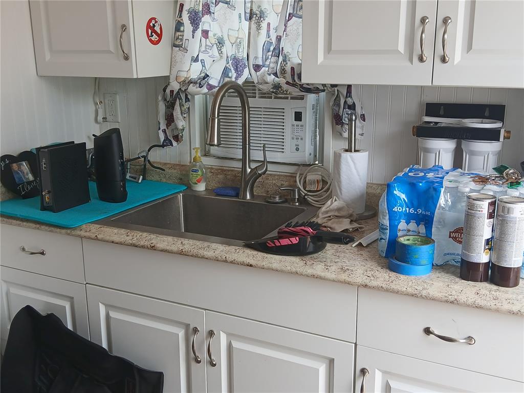A kitchen sink area features white cabinets, a granite countertop, and a window-mounted air conditioner — 2442 LIMEWOOD AVENUE, CLERMONT, FL