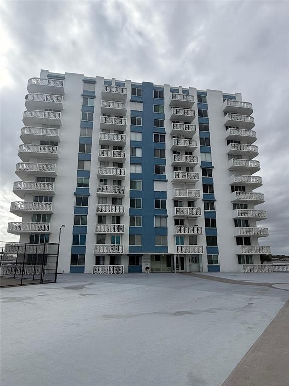 A multi-story residential building with white exterior walls and stacked balconies under a cloudy sky — 925 N HALIFAX AVENUE UNIT 102, DAYTONA BEACH, FL
