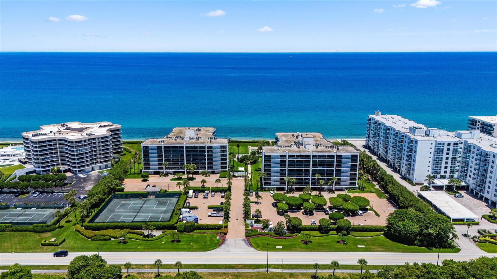 An aerial view shows several multi-story residential buildings near the ocean with tennis courts — 3440 S Ocean Boulevard, Palm Beach FL 33480, PALM BEACH, FL