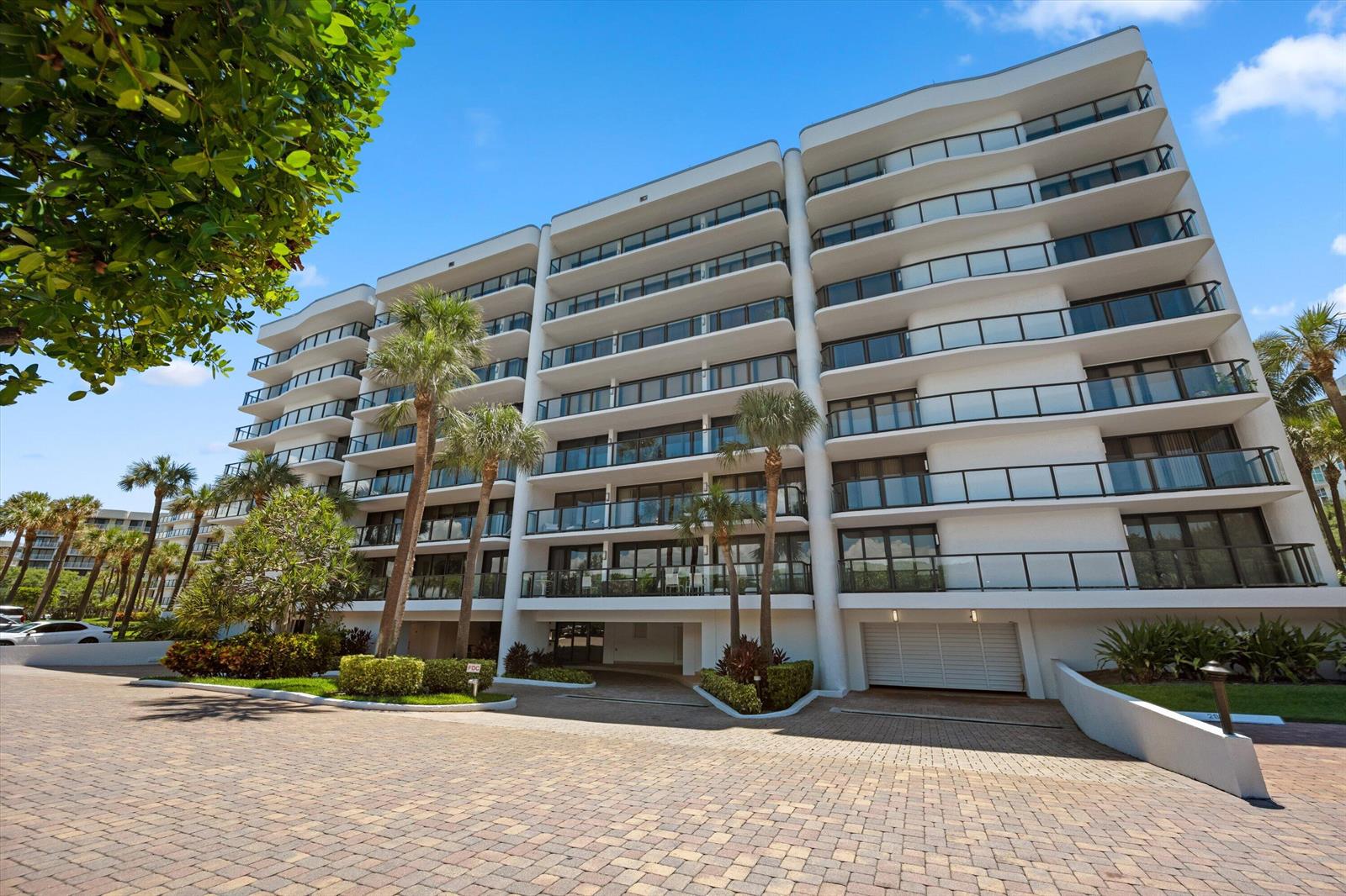 A multi-story white residential building with balconies and palm trees stands above a paved driveway — 3440 S Ocean Boulevard, Palm Beach FL 33480, PALM BEACH, FL