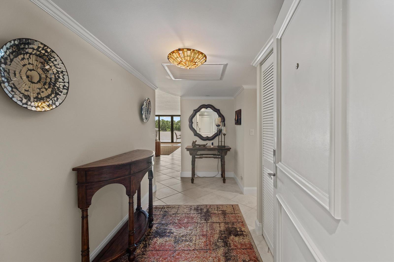 A tiled entryway features a wooden console table, a decorative wall mirror, and a rug — 3440 S Ocean Boulevard, Palm Beach FL 33480, PALM BEACH, FL