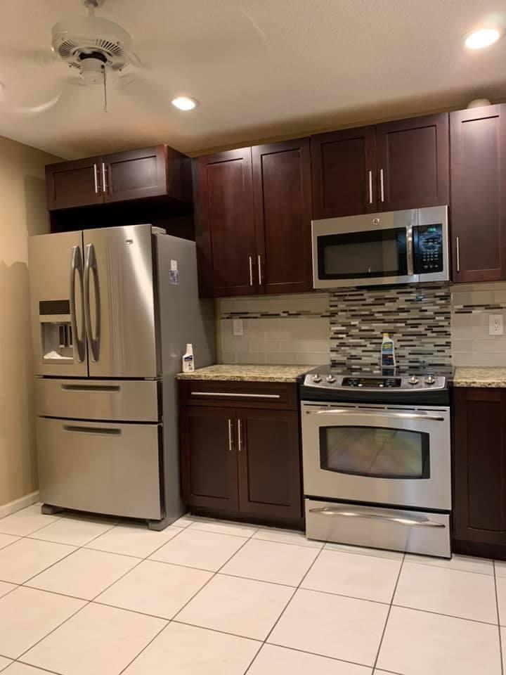 A kitchen featuring dark wood cabinets, stainless steel appliances, granite countertops, and a tiled backsplash — 9292 Sabal Ridge Circle # D, Boca Raton FL 33428, BOCA RATON, FL
