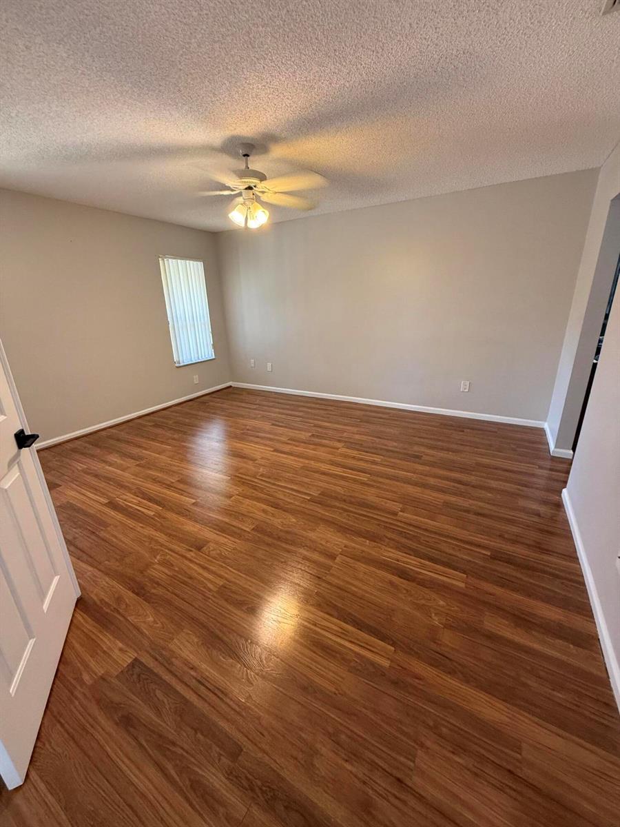 An empty room features light-colored walls, a ceiling fan, and wood-look laminate flooring — 9292 Sabal Ridge Circle # D, Boca Raton FL 33428, BOCA RATON, FL