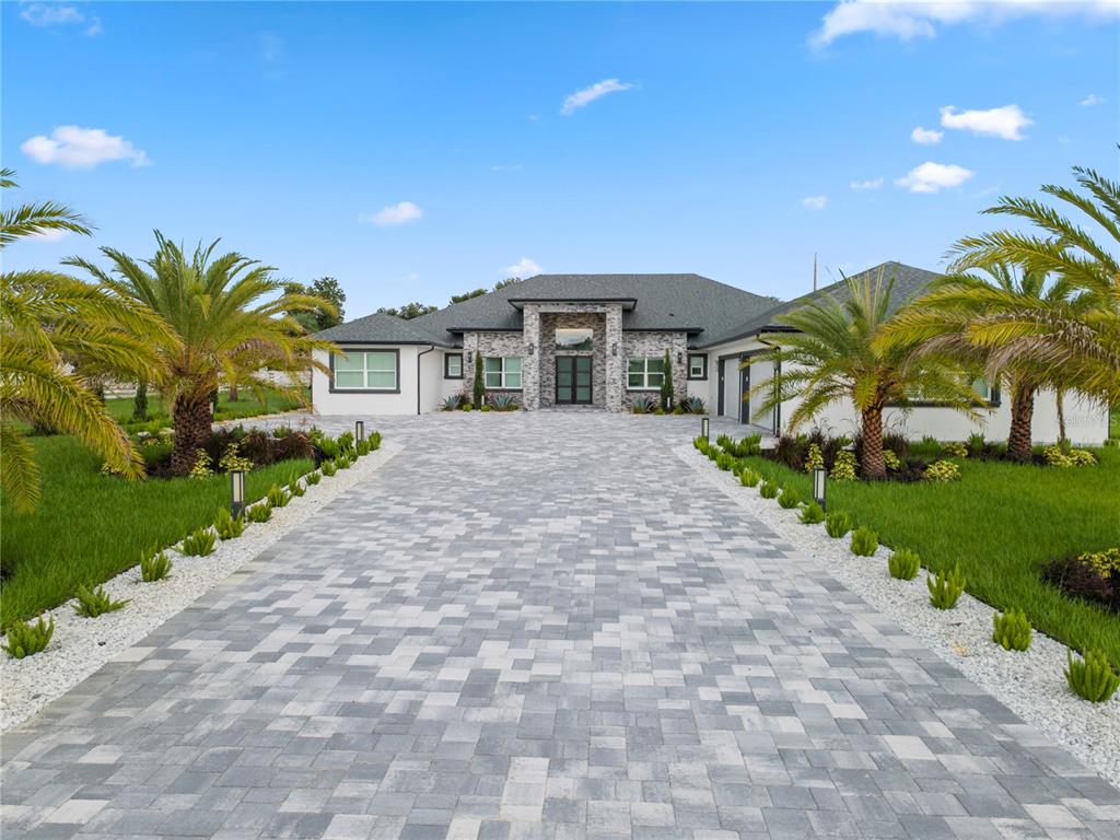 A paved driveway leads to the front entrance of a single-story house with stone accents — 34435 DONNA VISTA PLACE, EUSTIS, FL